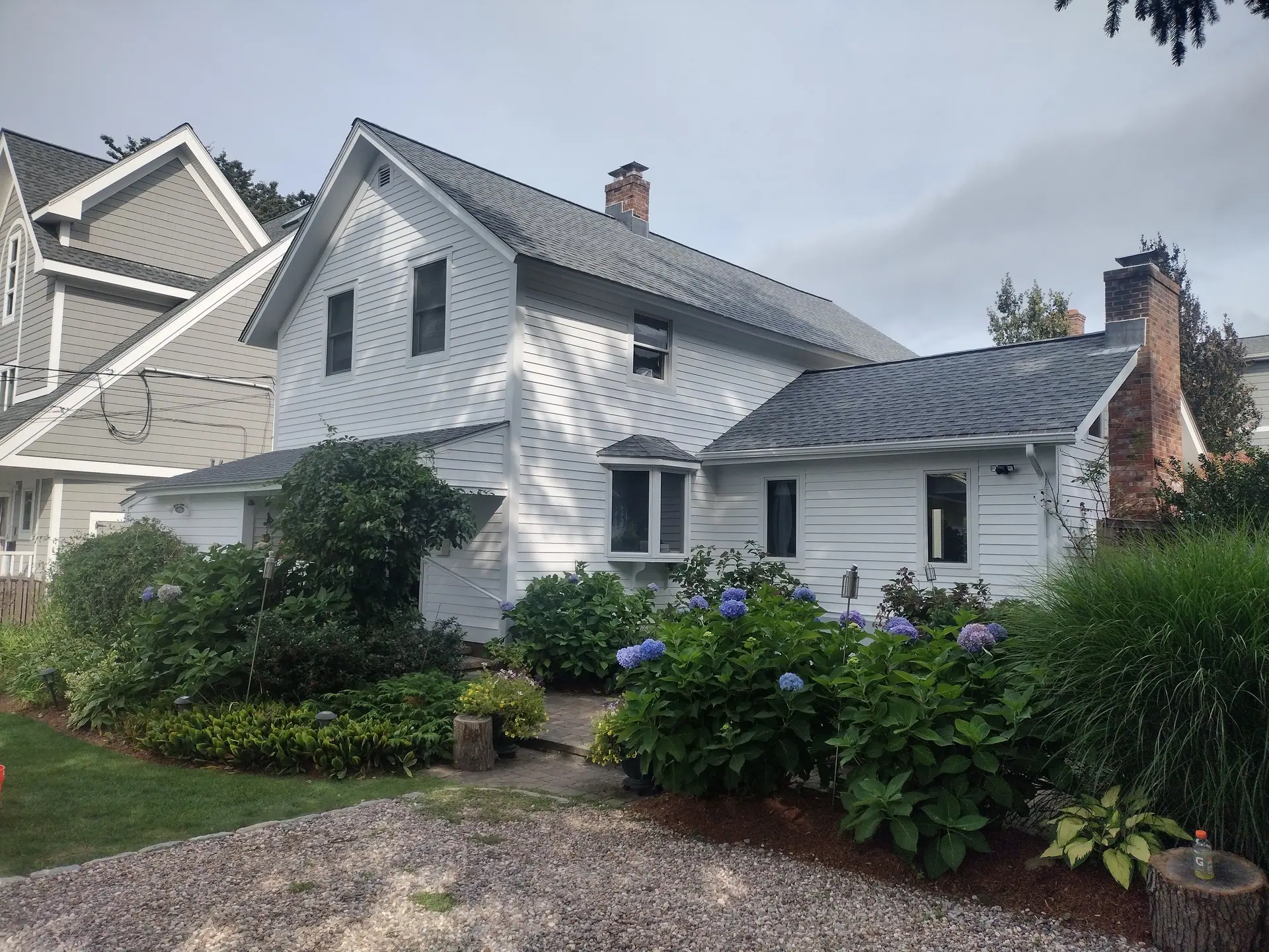 White farmhouse with fresh exterior paint and hydrangeas in front